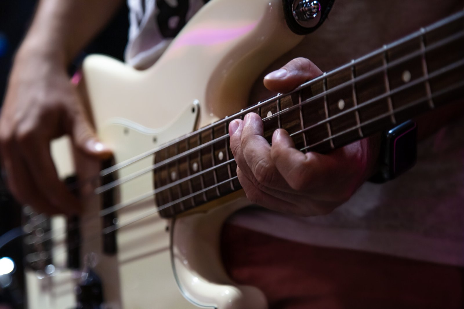 Musician playing white bass guitar close up. Part of bass guitar close up while playing.